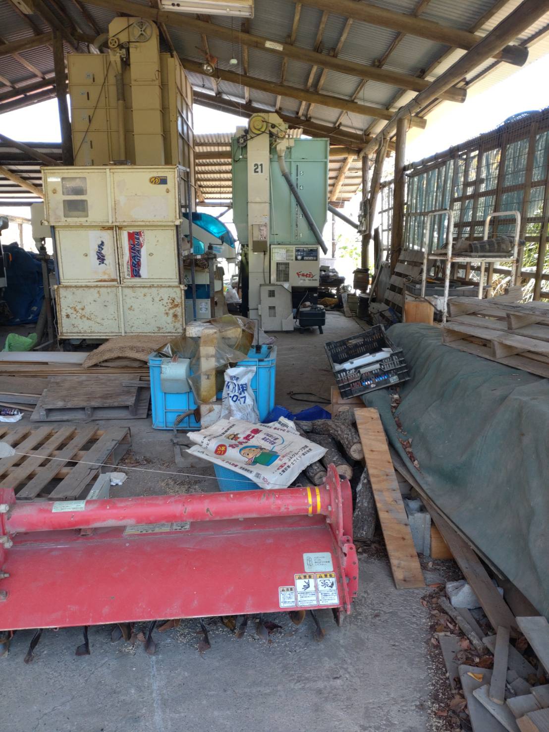 積み上げられた段ボールや棚に収められた資材類の片付け前の状態