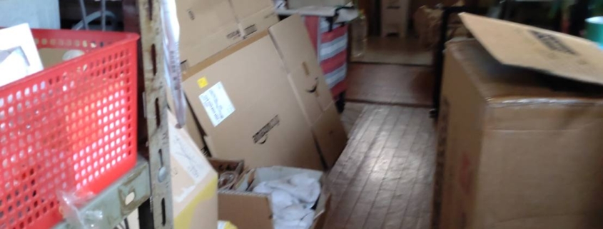 通路が段ボールや資材で塞がれた工場内の片付け前の様子|不用品片付け 世田谷区