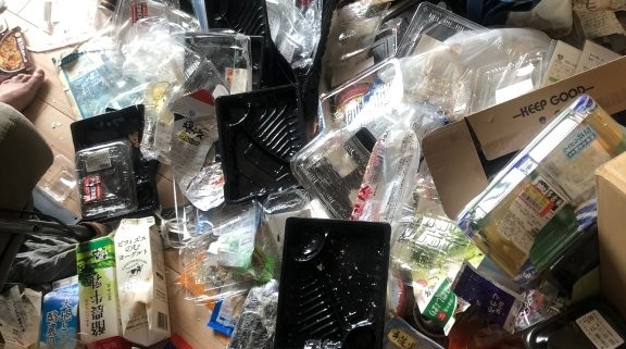 床一面に散乱した食品トレーやパック類を仕分け中の様子