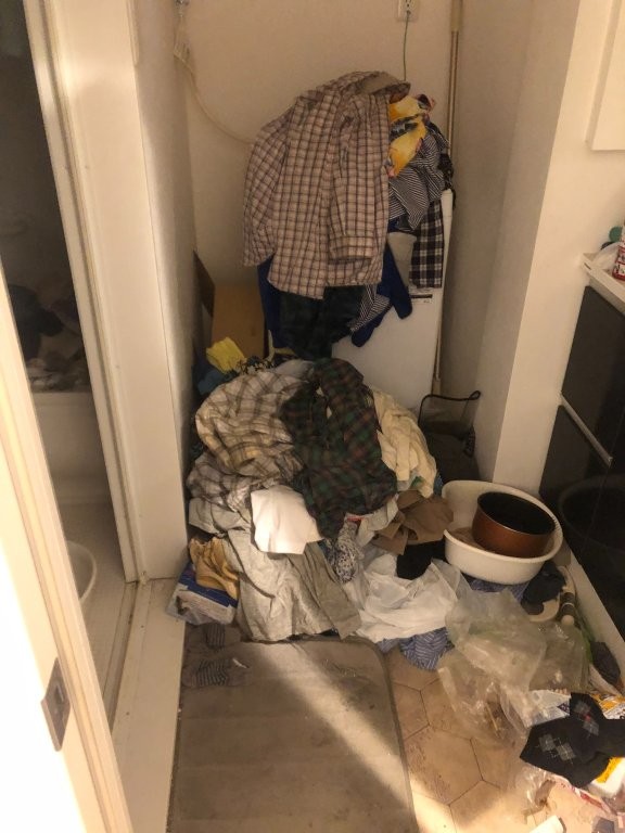 脱衣所に積み上がった衣類を分別している様子