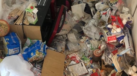 「床一面に散乱した食品パックや飲料パックを仕分ける前の様子｜ゴミ屋敷片付け 品川区南品川